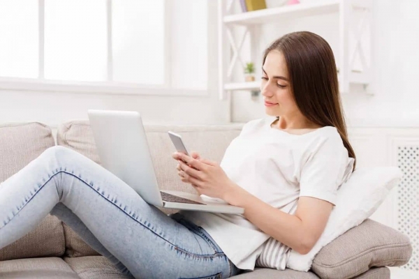 攝圖網(wǎng)_503598992_微笑的女孩在家里的沙發(fā)上隨意使用帶筆記本電腦的smatrphone黑發(fā)女孩在明亮的客廳里在線發(fā)短(企業(yè)商用).jpg 2-tuya.jpg